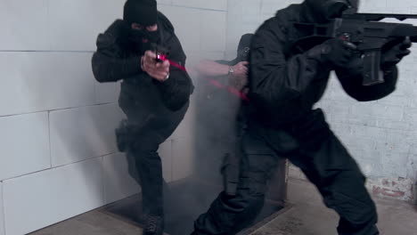 un equipo swat con pistolas y miras láser usa el sigilo cuando ingresan a un edificio a través de una escotilla en el piso