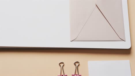 Close-up-of-notebook,-pens-and-stationery-arranged-on-beige-background,-in-slow-motion