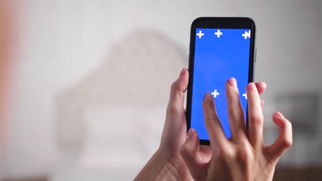 female person zooms in and out blue chromakey screen with fingers on surface.