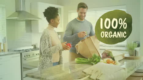 animation of 100 percent organic text over diverse couple preparing healthy meal in kitchen