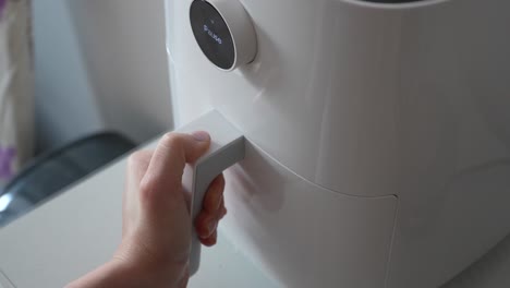 a close-up view of an air fryer drawer being opened to reveal freshly baked bread rolls inside, showcasing the convenient and healthy cooking method