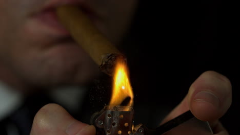 businessman lighting his cigar on black background