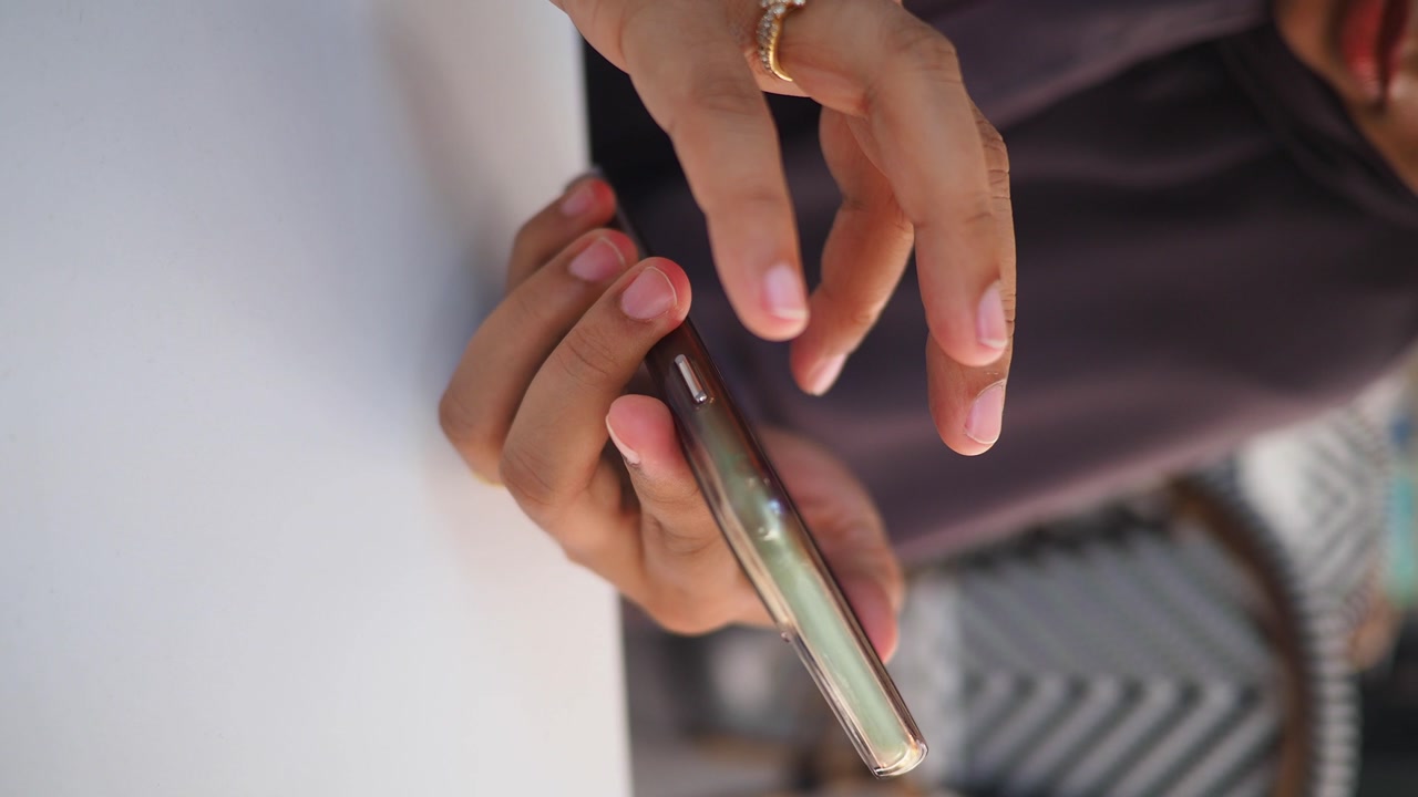 Close-up of Hands Holding and Pressing Buttons on a Smartphone
