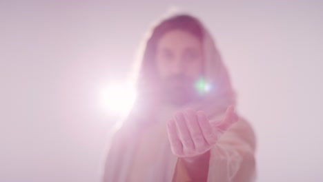 backlit shot of man with long hair and beard representing figure of jesus christ extending hand in friendship towards camera 1