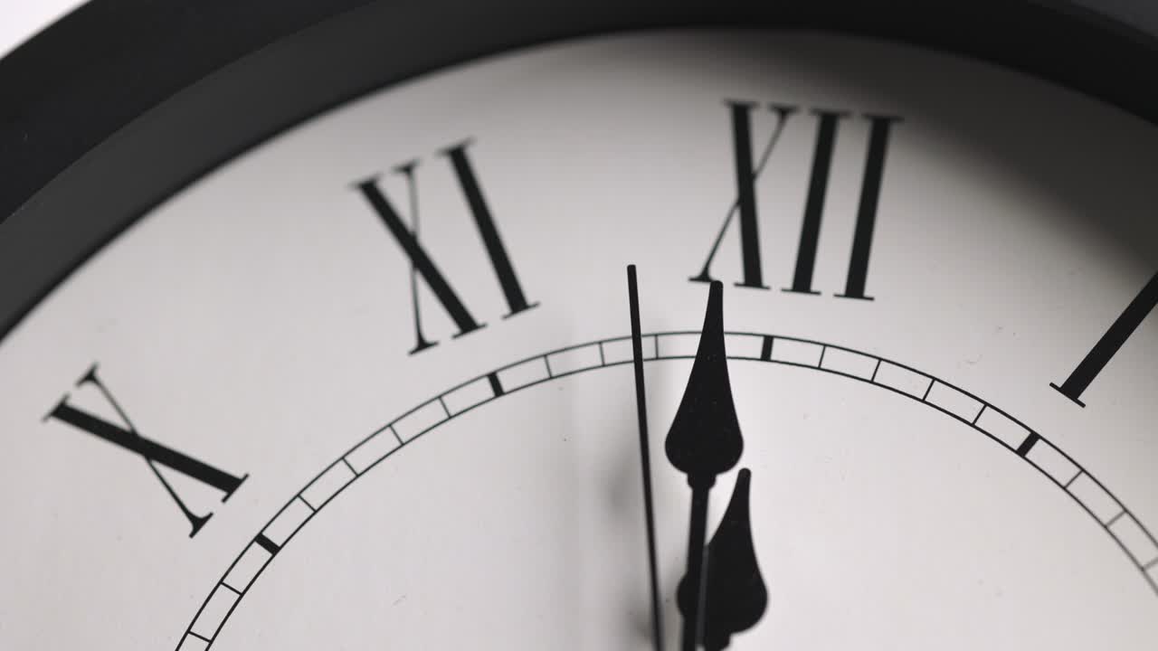 Filmato in time-lapse. Grande orologio da parete bianco. Imposta l'ora alle 12:00. La lancetta rossa dei minuti continua a girare. Numeri romani.
