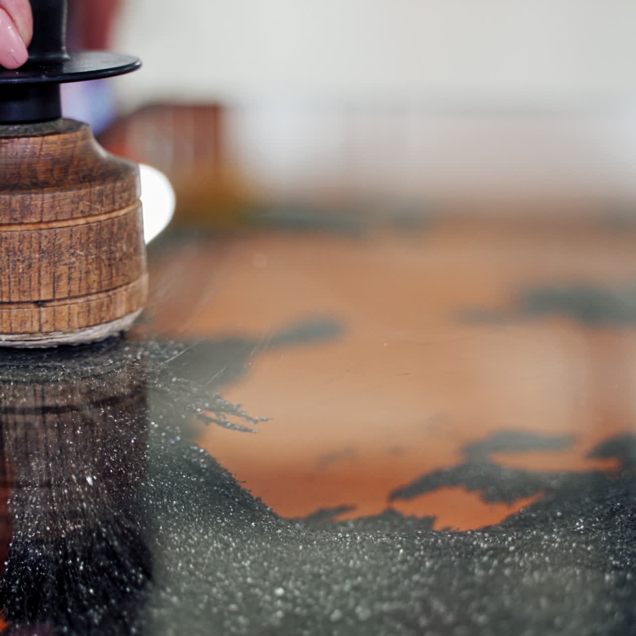 Hand holds brush and touches metallic filing on magnets. Iron shavings and magnet.