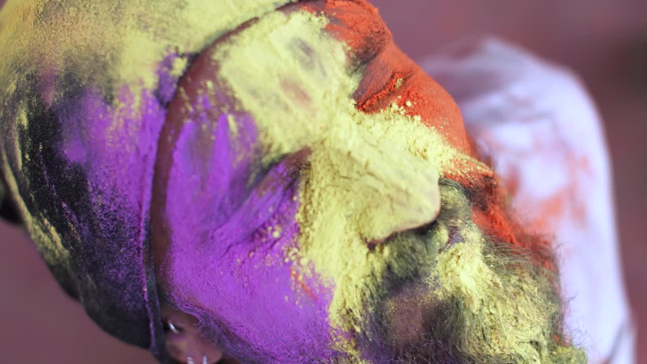 hombre indio de primer plano de la cara manchada con colores brillantes de holi