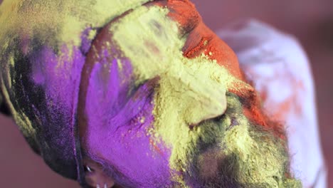 indian man close-up of face smeared with bright holi colors