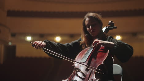 beautiful woman is playing cello in music hall female violoncellist on scene of opera house