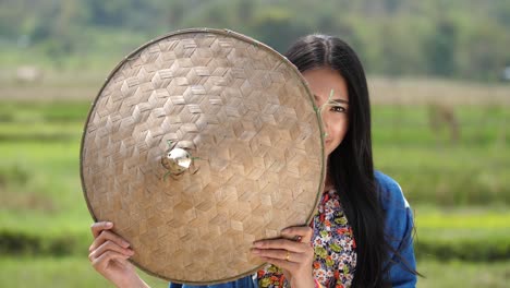 asian woman in traditional attire with straw hat in rice paddy