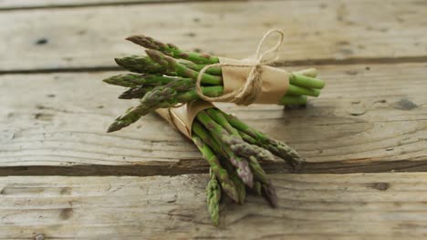 video of two fresh asparagus bundles on wooden background