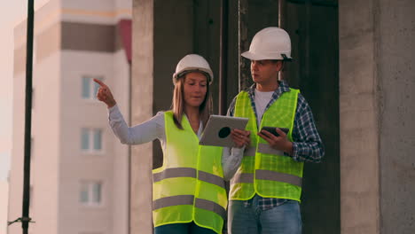 ingenieros o arquitectos tienen una discusión en el sitio de construcción mirando a través del plan de construcción. contre jour. ingenieros o arquitectes tienen una discusion