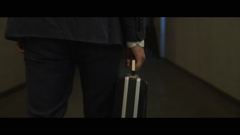 man walking down a corridor with a rabbit head carries a briefcase
