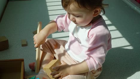 baby girl playing wooden toys on the floor