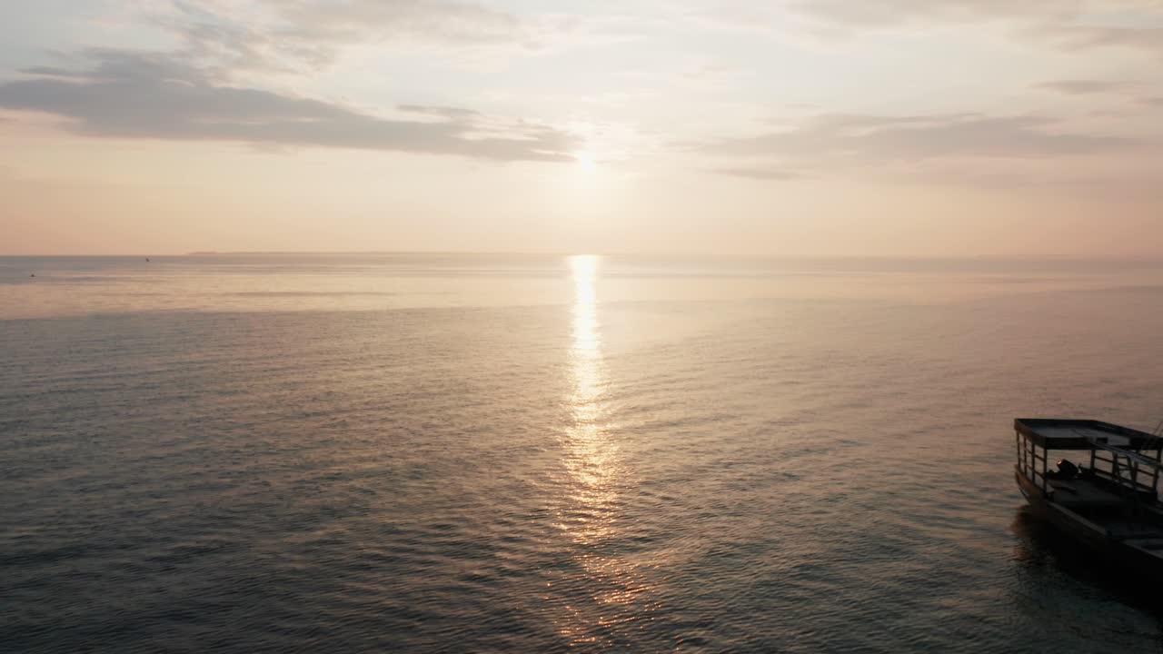 Aerial drone view flying over the ocean with lots of phising canoes during sunrise in Zanzibar, Tanzania.