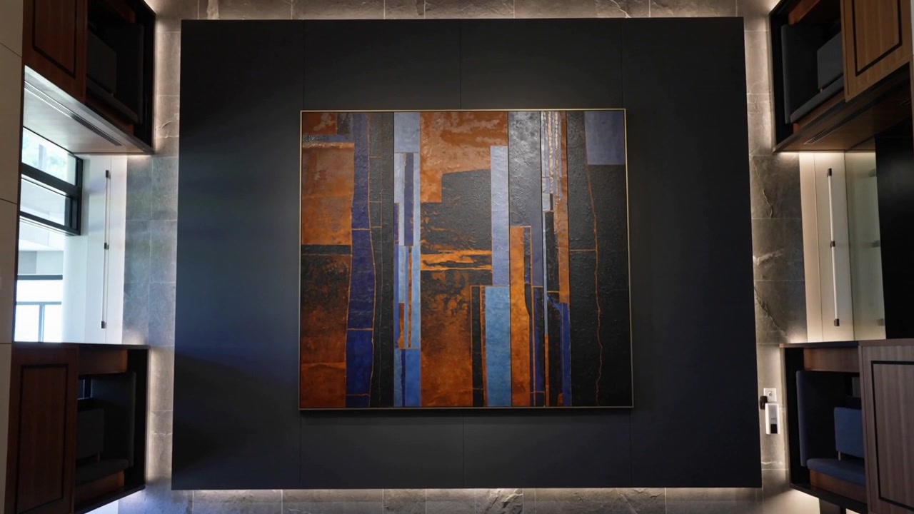 La telecamera ruota partendo capovolta, livellando e centrando un grande dipinto astratto, rivelando una finestra.