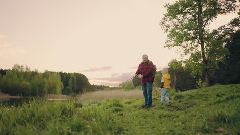 pescare sulla riva di un bellissimo lago forestale il nonno e il nipote stanno trascorrendo del tempo insieme