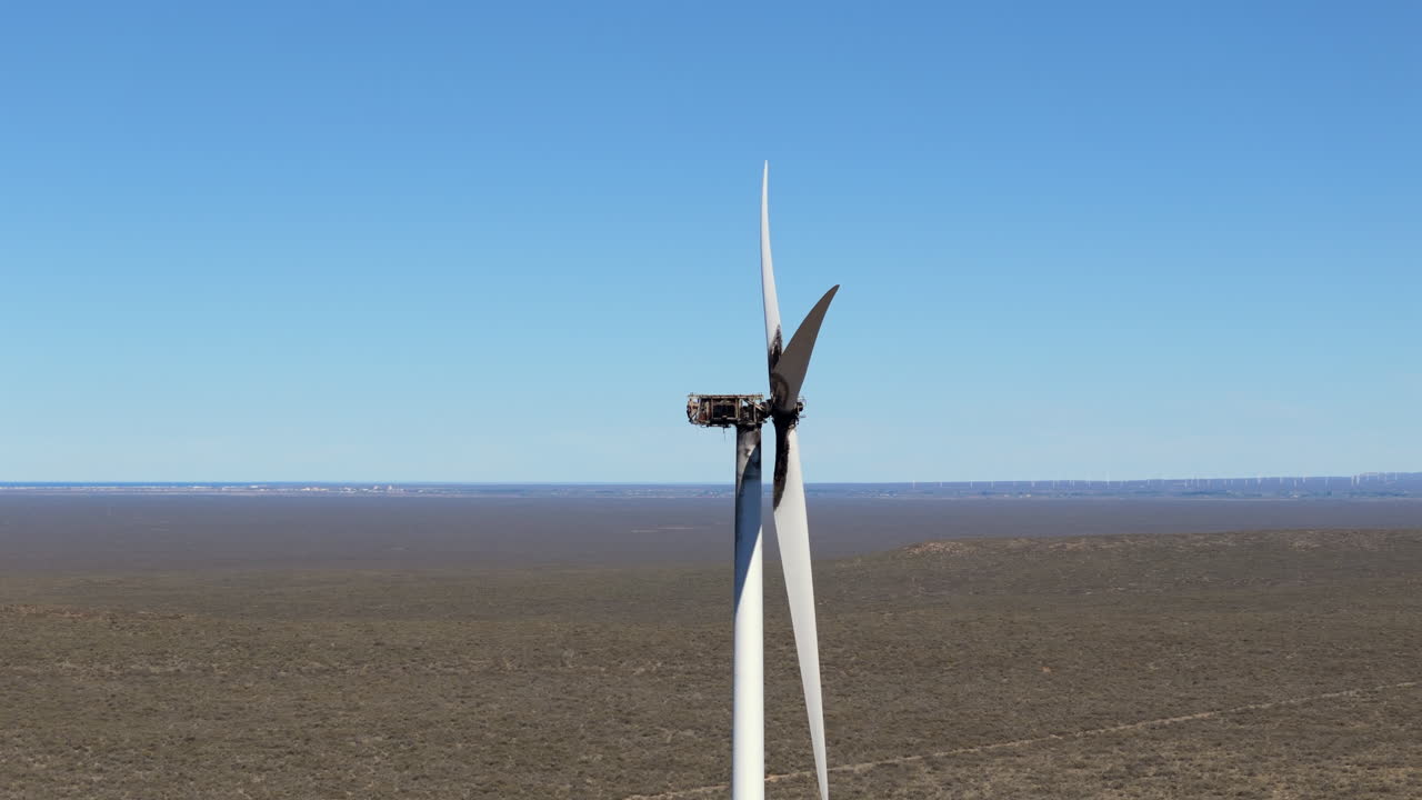 Aerial slow-motion view of a ruined electric windmill in the desert.
