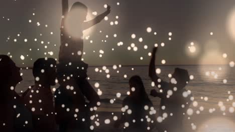 White-glowing-spots-moving-against-group-of-friends-partying-on-the-beach