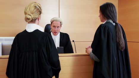 two lawyers standing and speaking with the judge