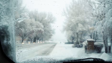 Innenansicht-Der-Frontscheibe-Eines-Autos-Mit-Nassem-Schnee,-Der-Darauf-Fällt-Und-Scheibenwischer,-Der-Ihn-Reinigt