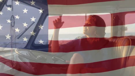 Animation-of-American-flag-waving-over-Caucasian-woman-looking-out-of-car-window-on-beach