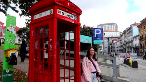 Tourist-checks-typical-red-British-phone-box-in-Porto,-Portugal