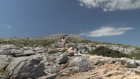 Upwards-pedestal-of-girl-hiking-up-rocky-mountain-in-slow-motion