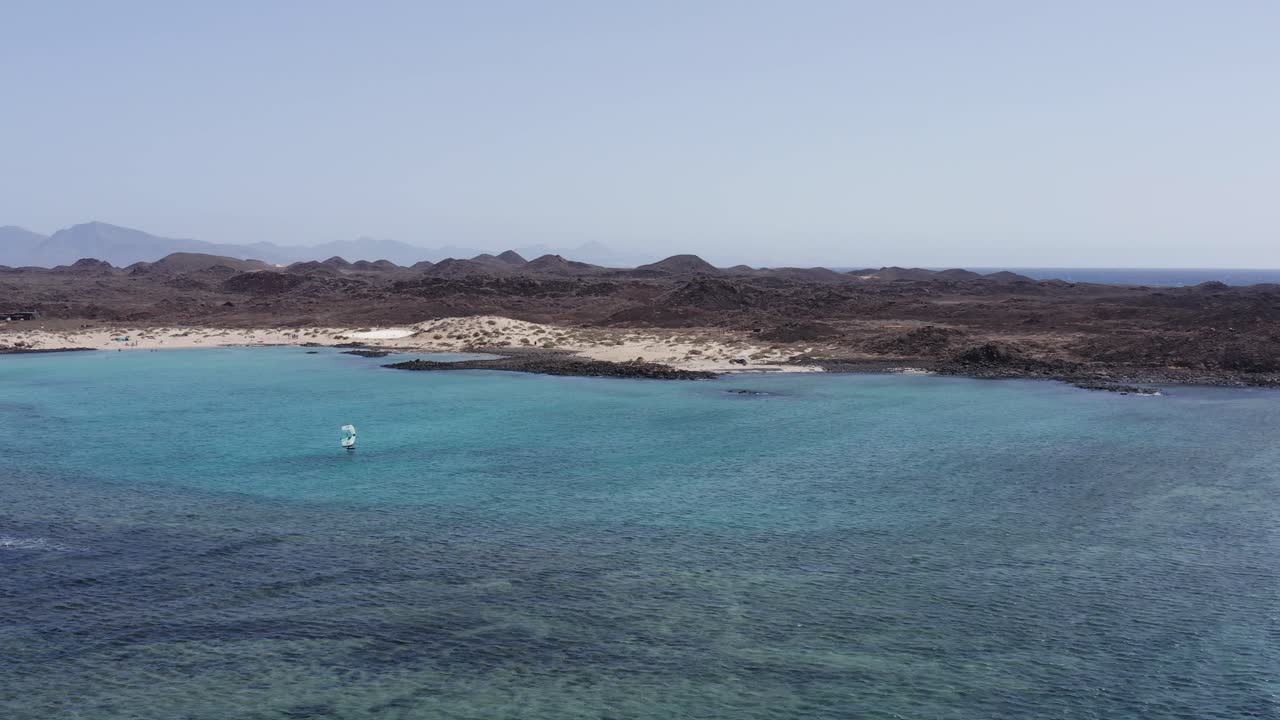 toma aérea de un hombre montando una tabla de aluminio con una cometa de ala