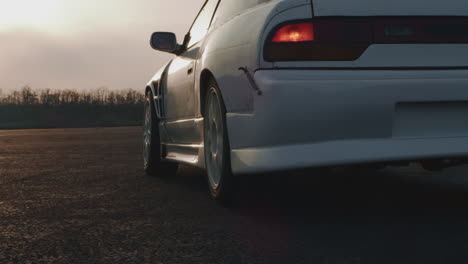 white drift car on a track at sunset