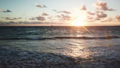 a beautiful shot of waves crashing on a hawaiian beach with a colorful sunrise on the horizon