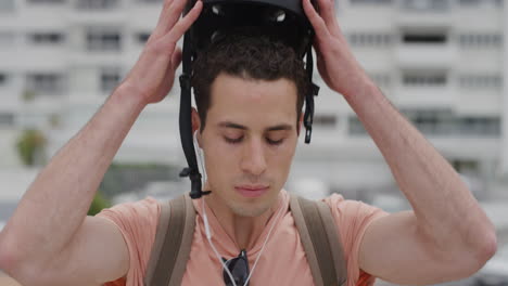 portrait young man takes off helmet looking serious wearing earphones listening to music attractive male in urban city safety protection