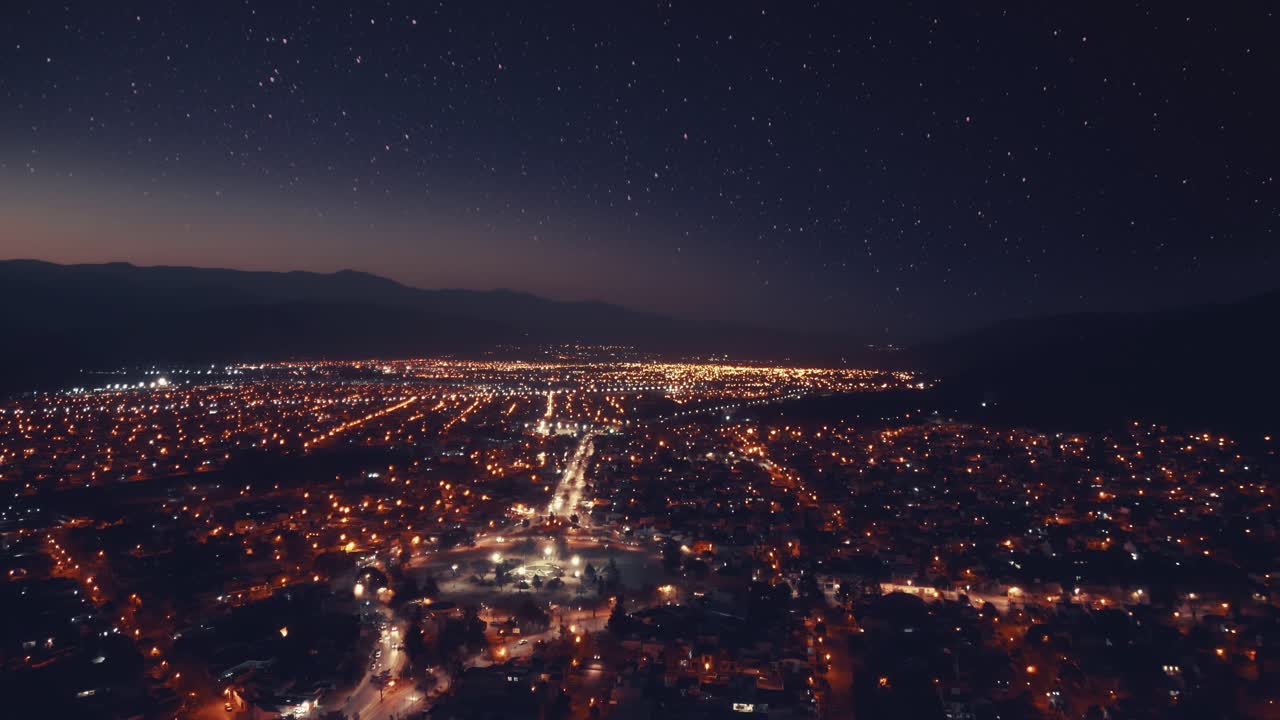 Vista aerea time-lapse di una città di notte sotto un cielo stellato