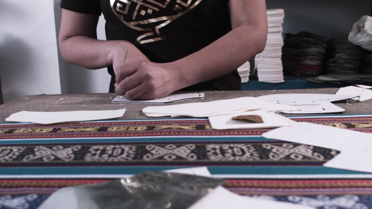 A woman measures and punches pieces of colorful textile