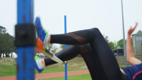 vista lateral de una atleta caucásica practicando salto de altura en un recinto deportivo 4k