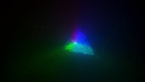 las formas abstractas crean luz de diferentes colores. triángulo creado jugando rayos de luz moviéndose en la oscuridad y el humo.