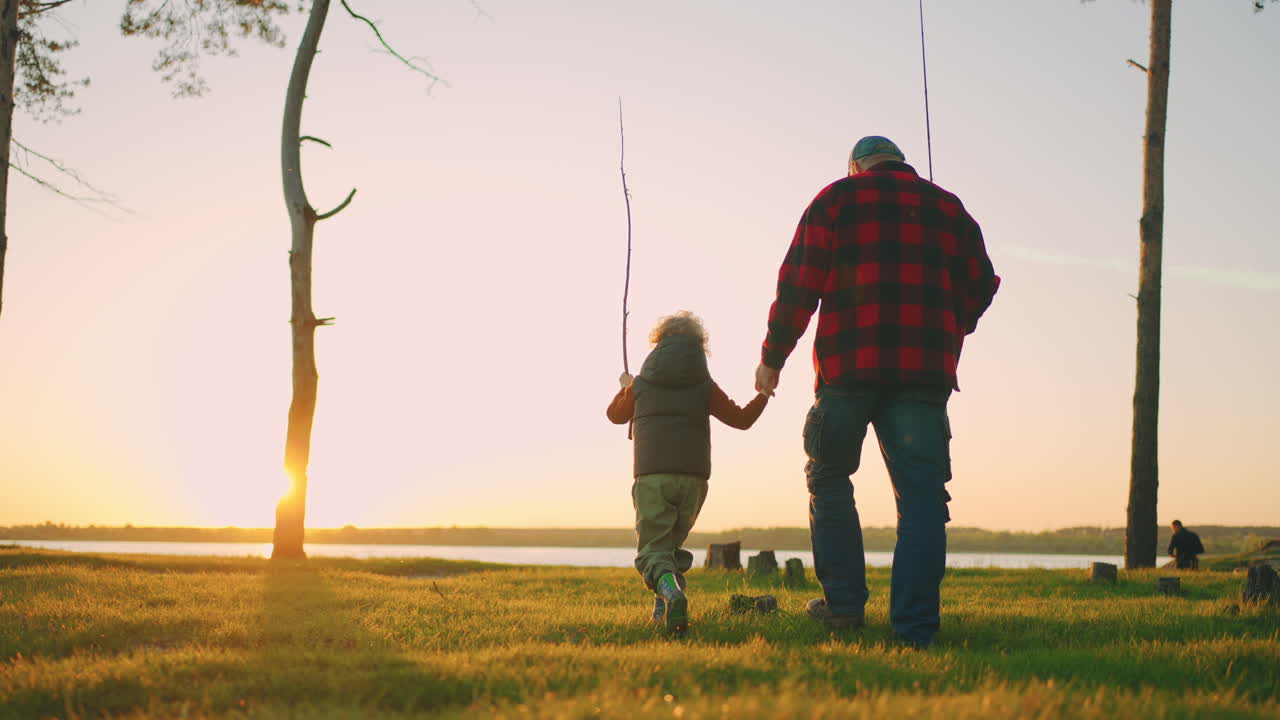 little boy is spending time with grandfather in nature old fisher and child are going to river shore for fishing