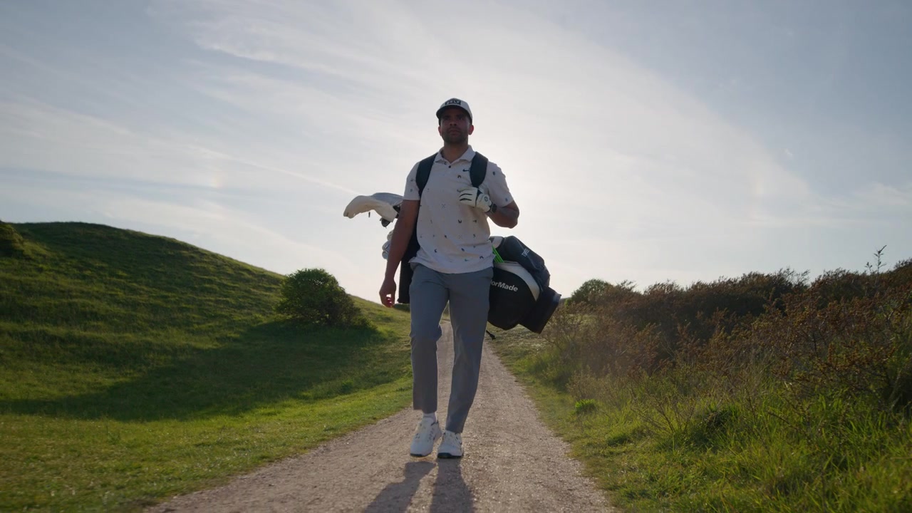 Pro Male Golfer Walks on Course during Golden Hour, Front Follow Slomo
