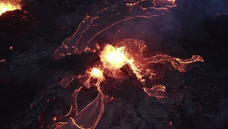 volcano crater during eruption with flowing lava and smoke