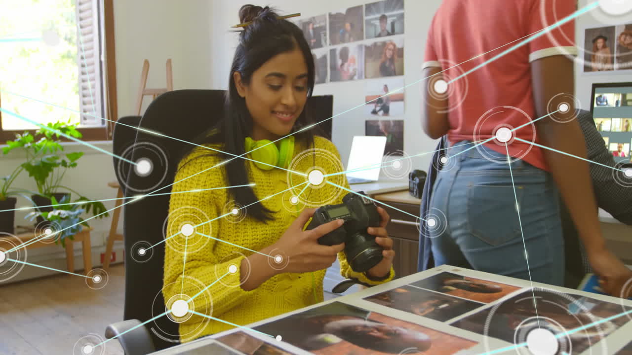 Network of connections animation over woman reviewing photographs in office
