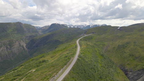 vehicle driving on long narrow mountain road with cloudy sky at vikafjell, norway