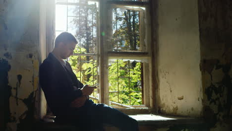 unhappy young businesswoman writing sms sitting in an abandoned house near the window concept bankru