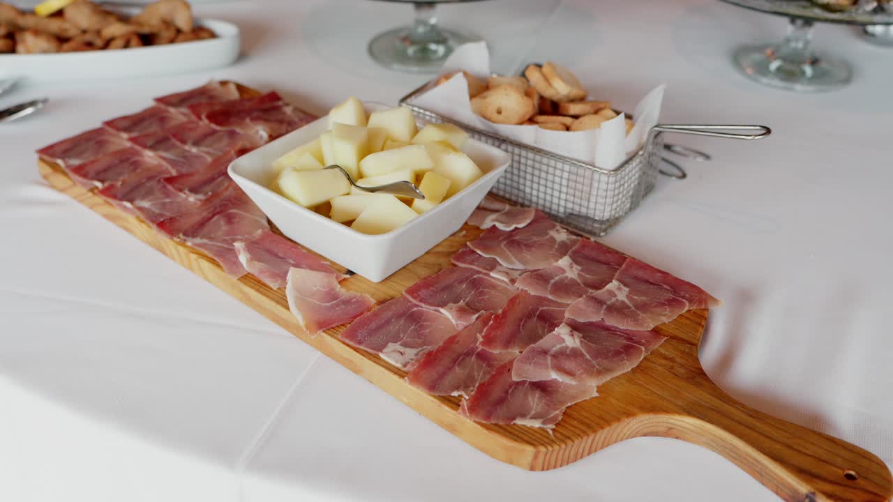 Cured ham with melon cubes served on a wooden board at a catered event or gathering