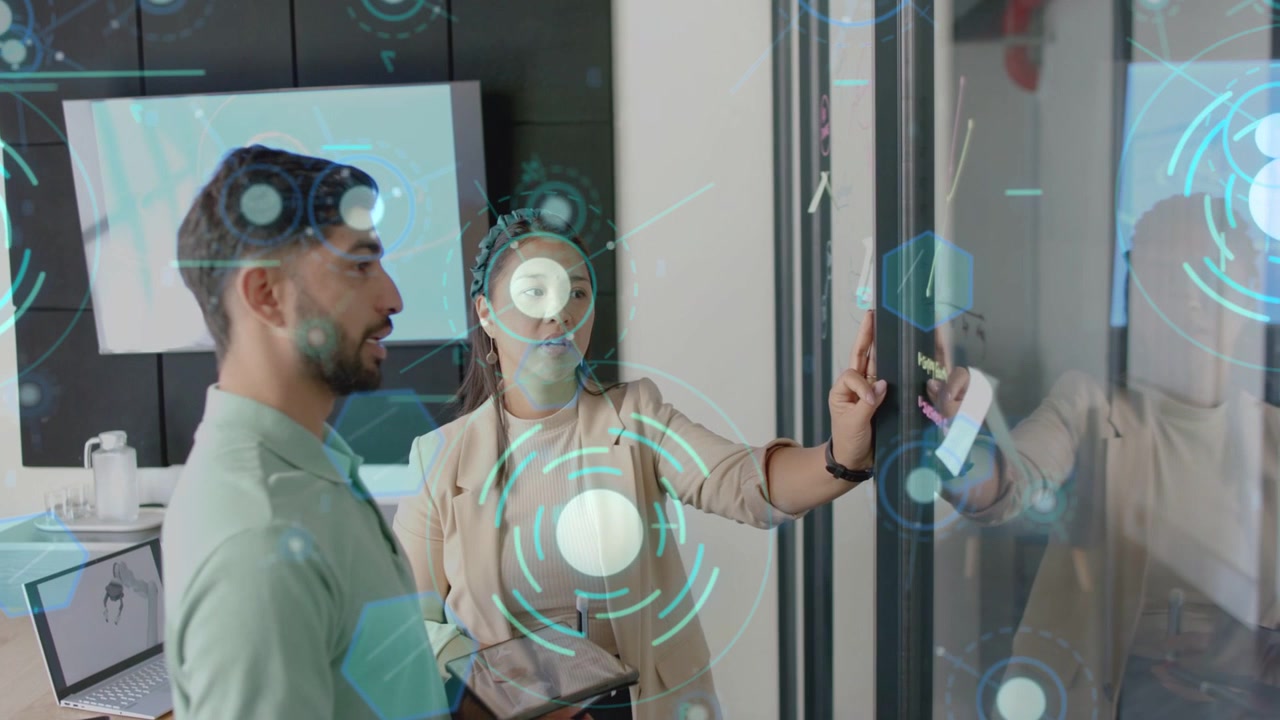 Woman tapping glass panel initiating teal UI overlay, man holding tablet analyzing business data