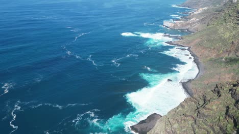 Vista-Aérea-De-Un-Acantilado-Gigante-Con-Las-Poderosas-Olas-Del-Océano-Rompiendo-En-Un-Hermoso-Día-Soleado-En-Tenerife,-Islas-Canarias