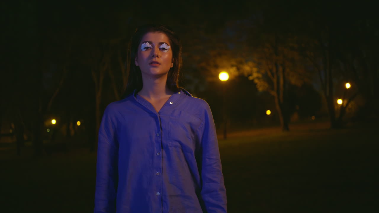 Mysterious woman standing solitude illuminated by park night lanterns closeup