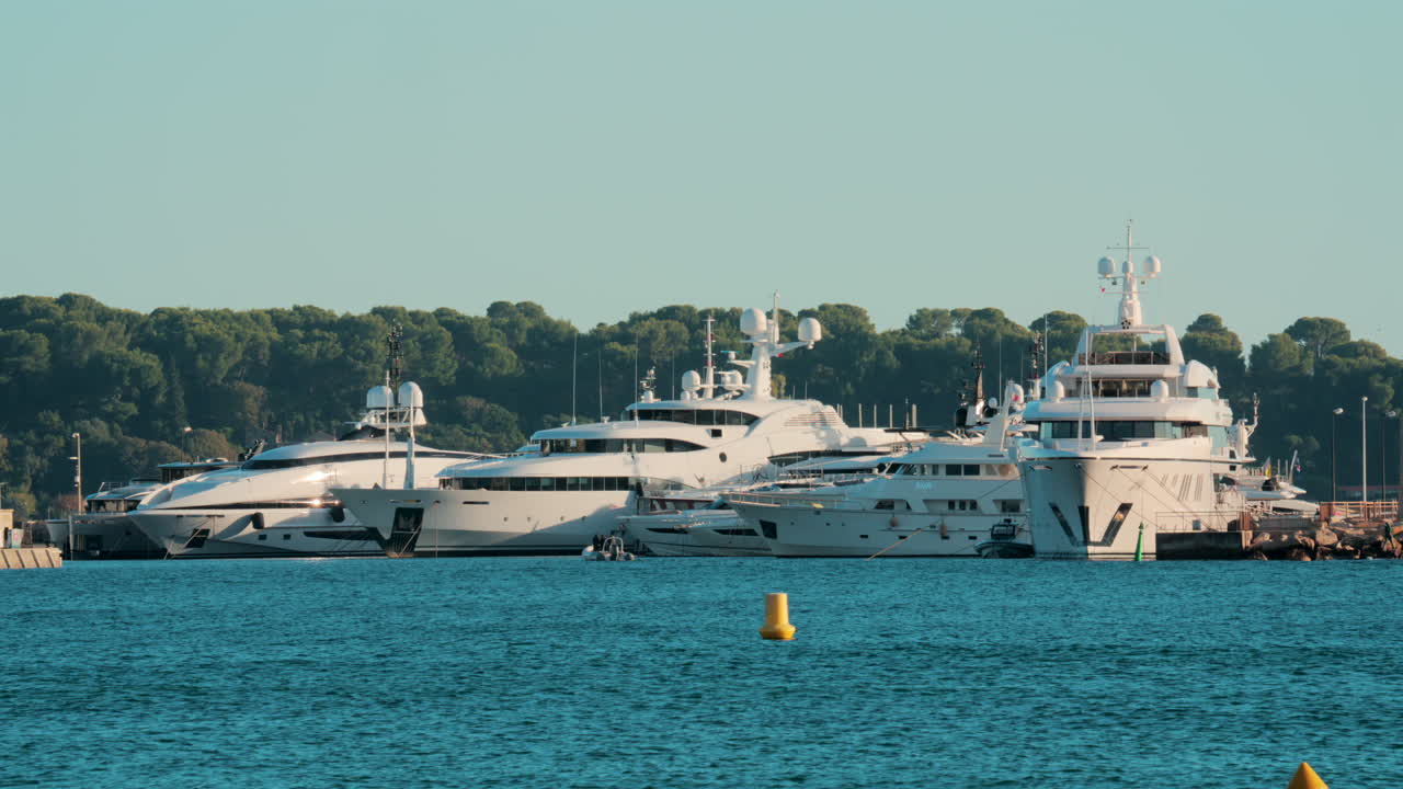 Dozens of luxury yachts anchored in thePort Pierre Canto in Cannes, with scenic coastal architecture and calm blue sea
