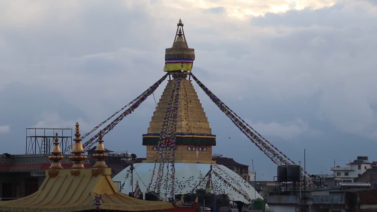 Boudhanath stupa with colorful prayer flags and golden spire standing tall under cloudy evening sky in Kathmandu symbolizing peace spirituality and Buddhist culture Outdoors