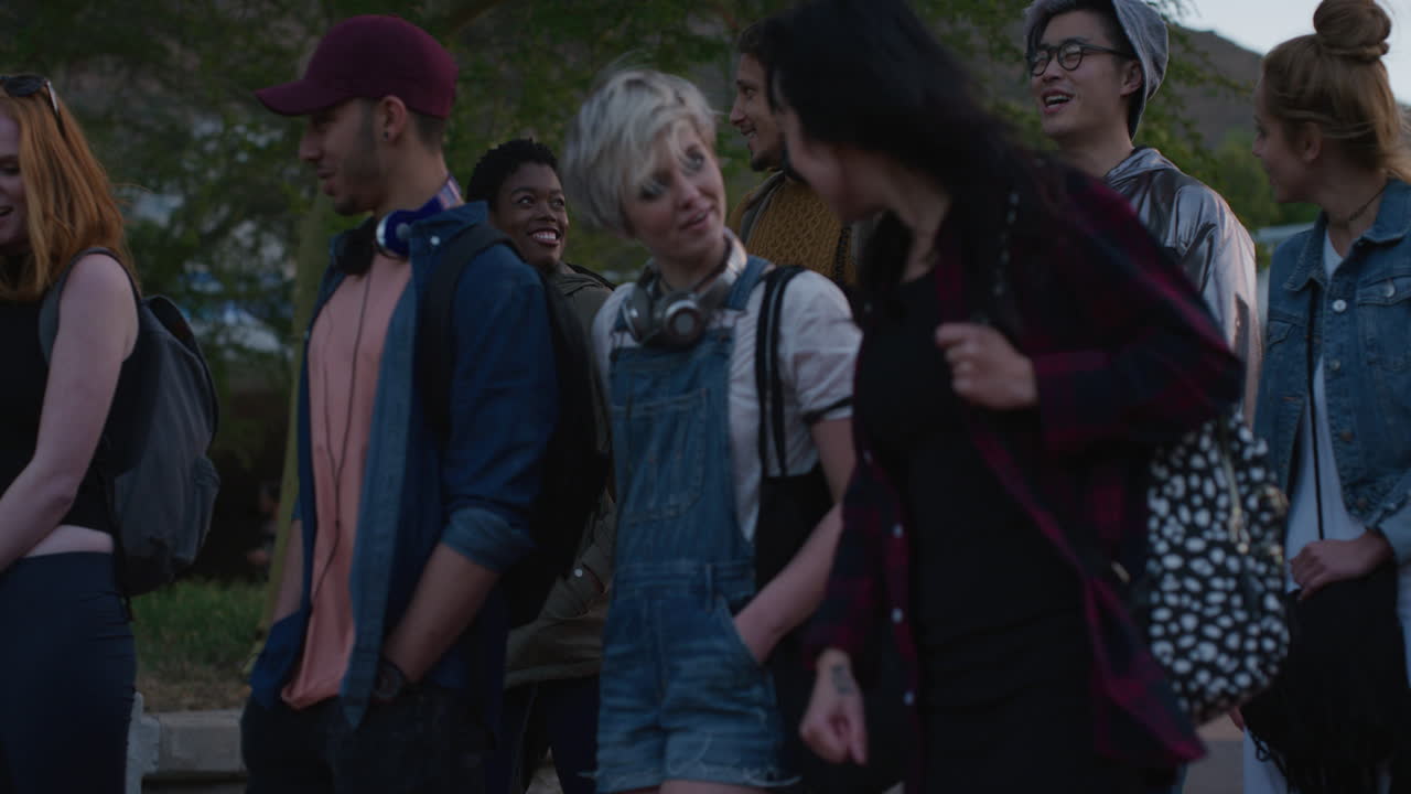 함께 대화하는 다이빙 친구들의 초상화 그룹 도시를 산책하고 사교를 즐기는 젊은 학생들이 저녁 이야기를 즐기고 슬로우 모션으로 어울립니다.