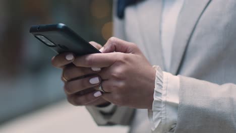 close up of muslim businesswoman checking messages on mobile phone standing outside office in city